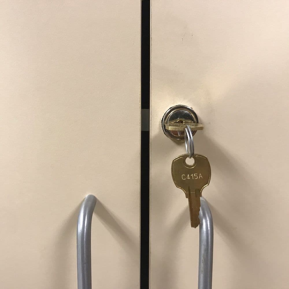 Key inserted in lock of a beige cabinet door, labeled C15A.