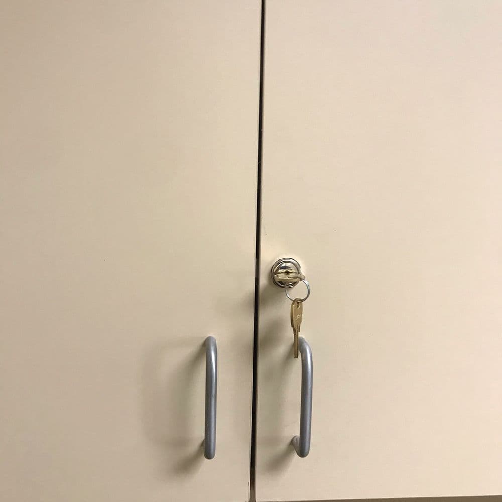 Locked cabinet with silver handles and a key inserted in the lock.