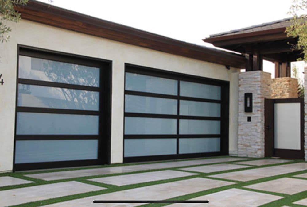 Modern home exterior showcasing glass panel garage doors and stone accents.