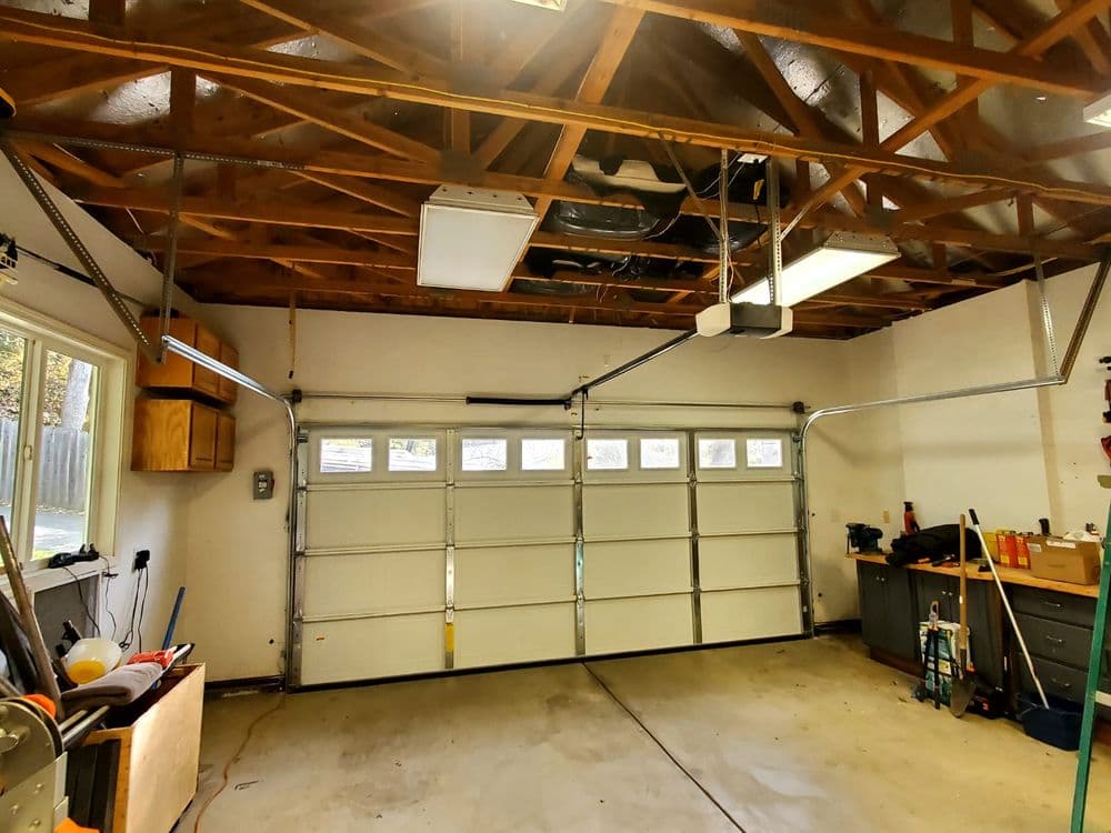 Spacious garage interior with double doors, wooden beams, and tools neatly organized.