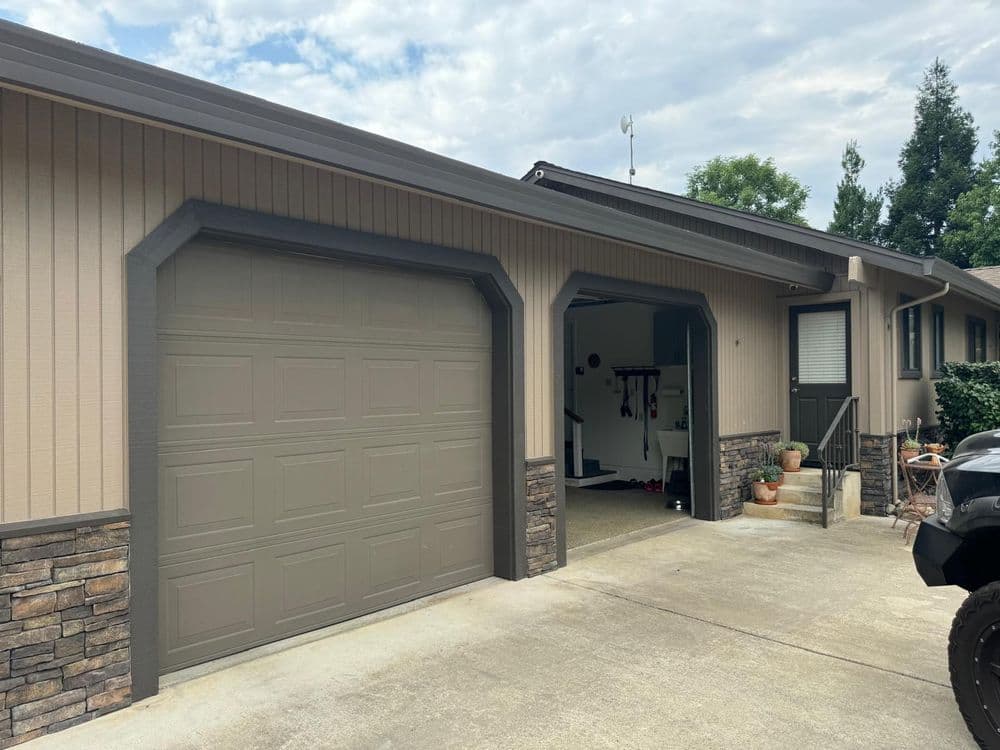 Exterior view of a modern home garage with stone accents and a paved driveway.