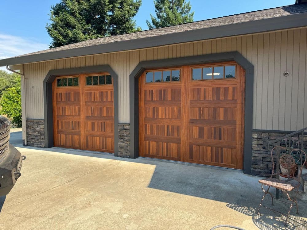 Modern wooden garage doors on a house with stone accents and a clear blue sky.