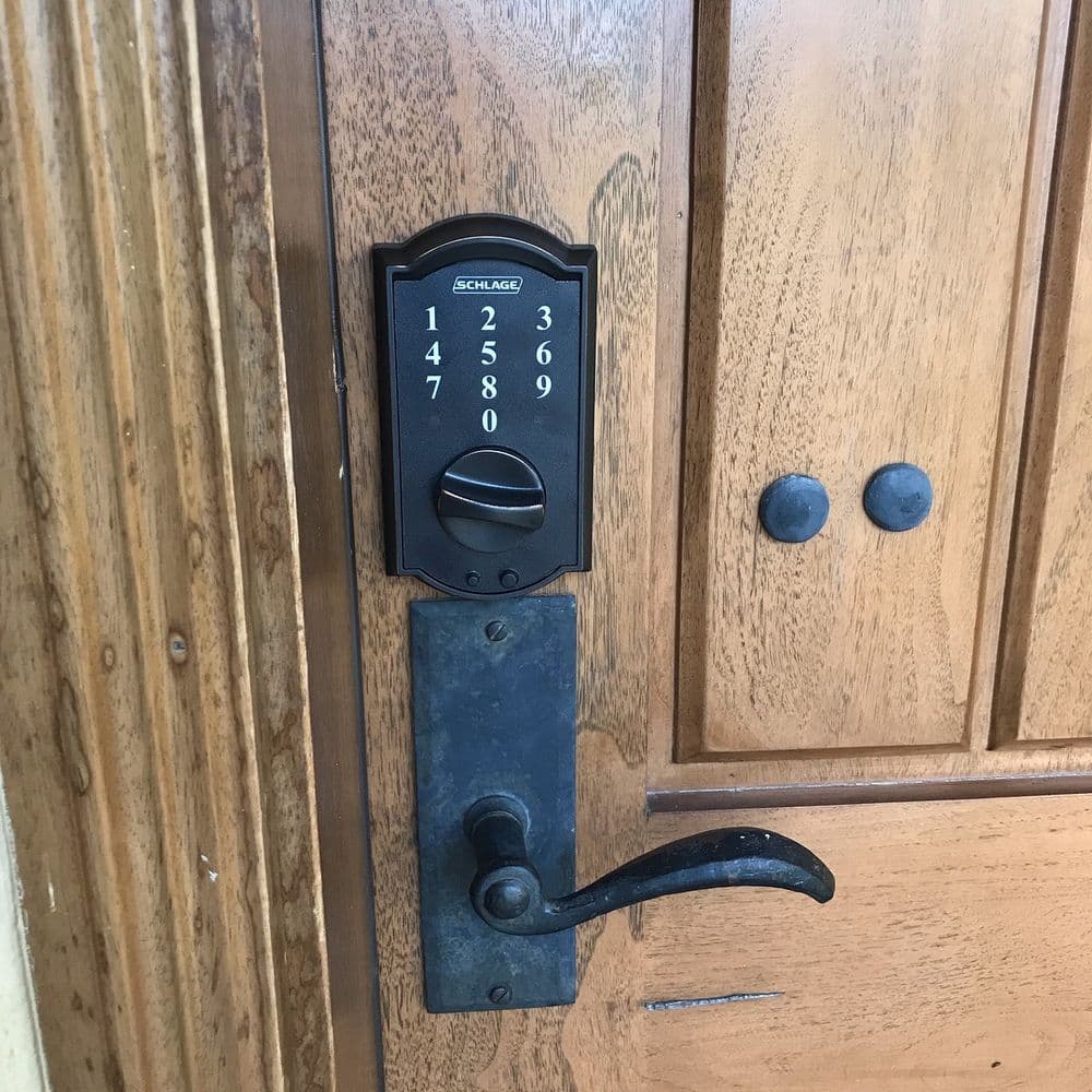 Schlage keypad door lock on a wooden door with a vintage handle. Secure entry solution.