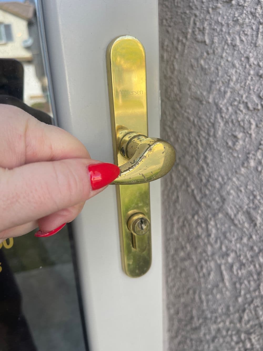 Hand holding a gold door handle, demonstrating how to open a door.