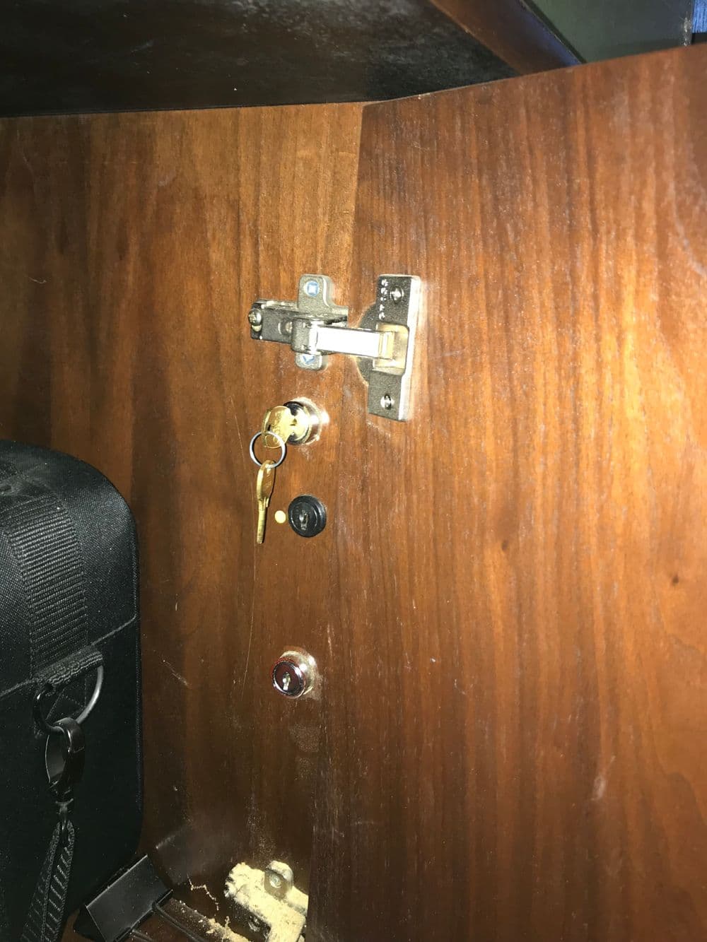 Wooden furniture locking mechanism with key inserted and visible hardware.