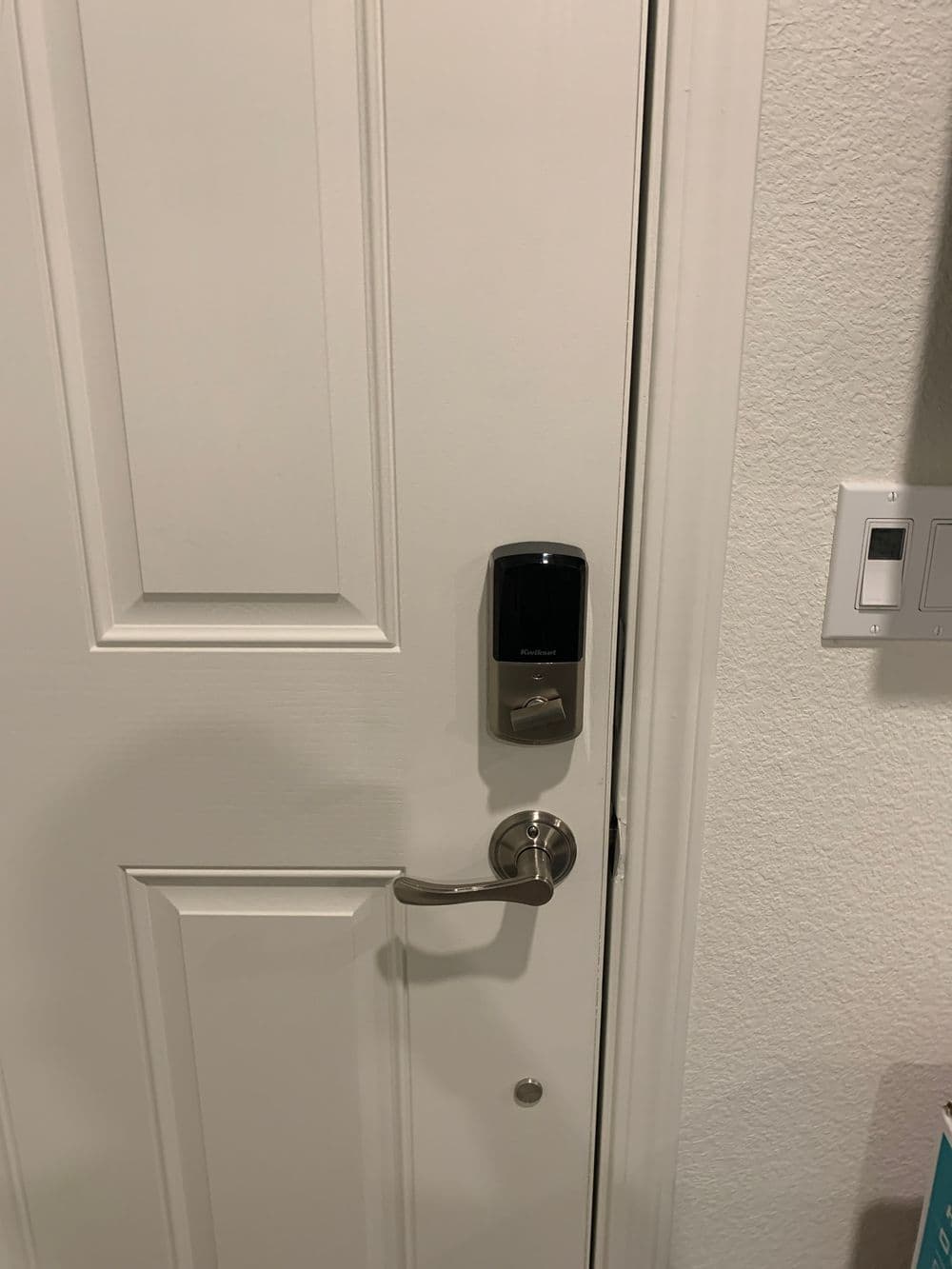 Smart lock installed on a modern white door, featuring keypad and handle for secure access.