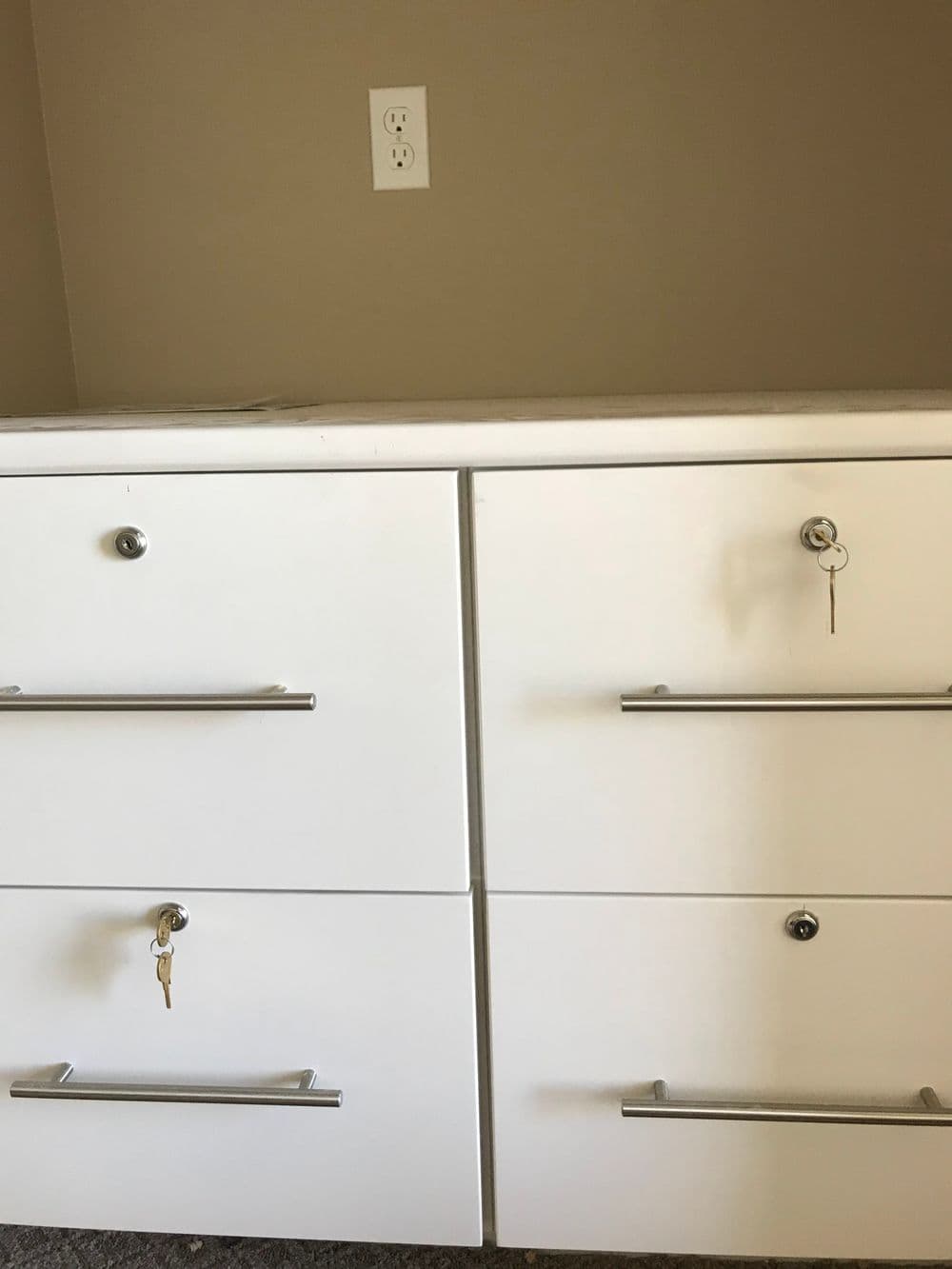 White filing cabinet with four drawers, featuring keys and modern handles.