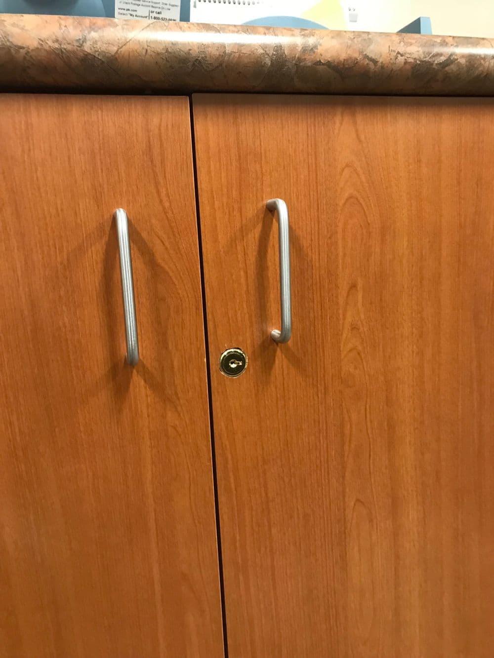Wooden cabinet doors with metallic handles and a keyhole for secure locking.