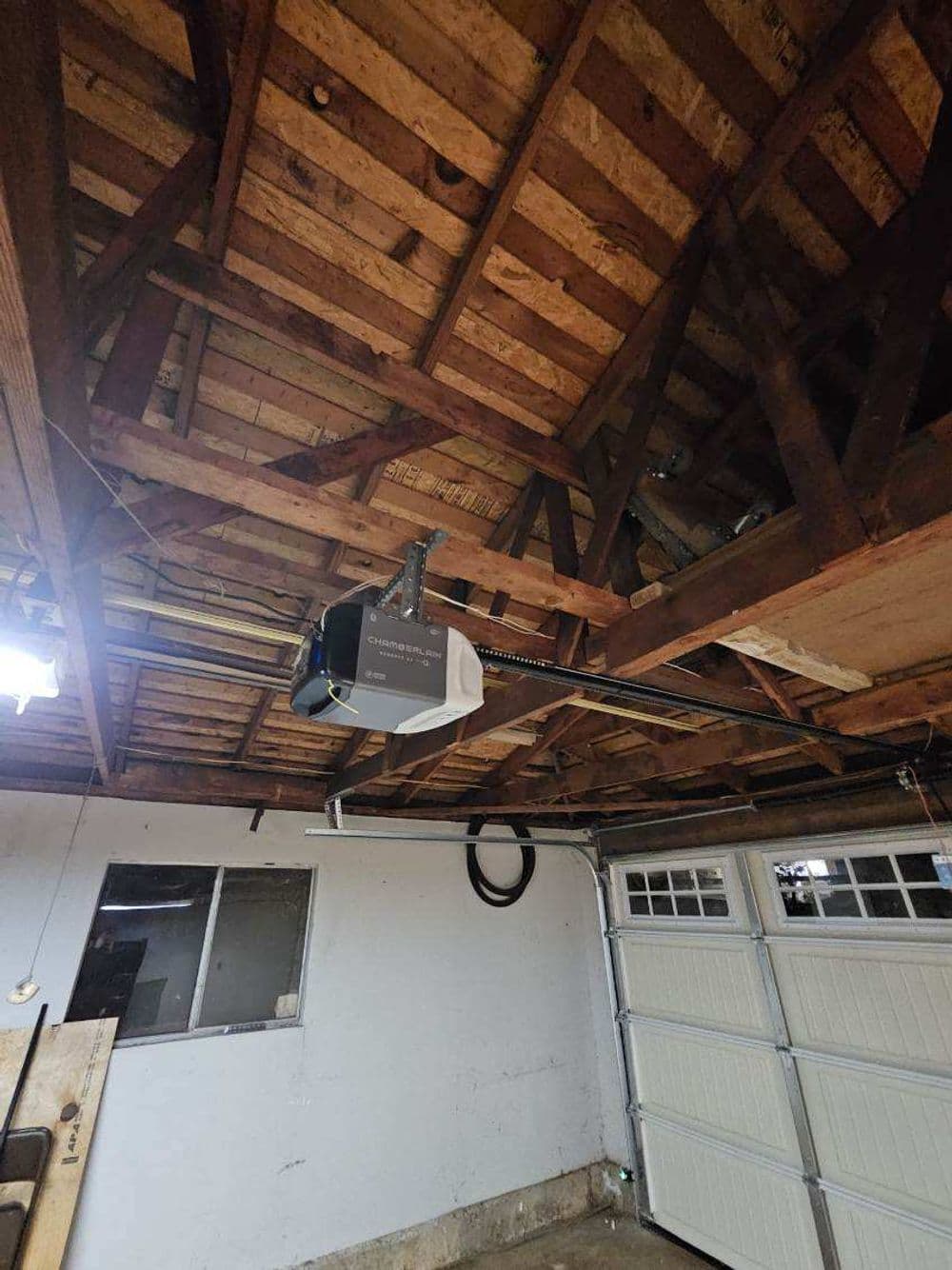 Garage interior with exposed wooden beams and a ceiling-mounted garage door opener.