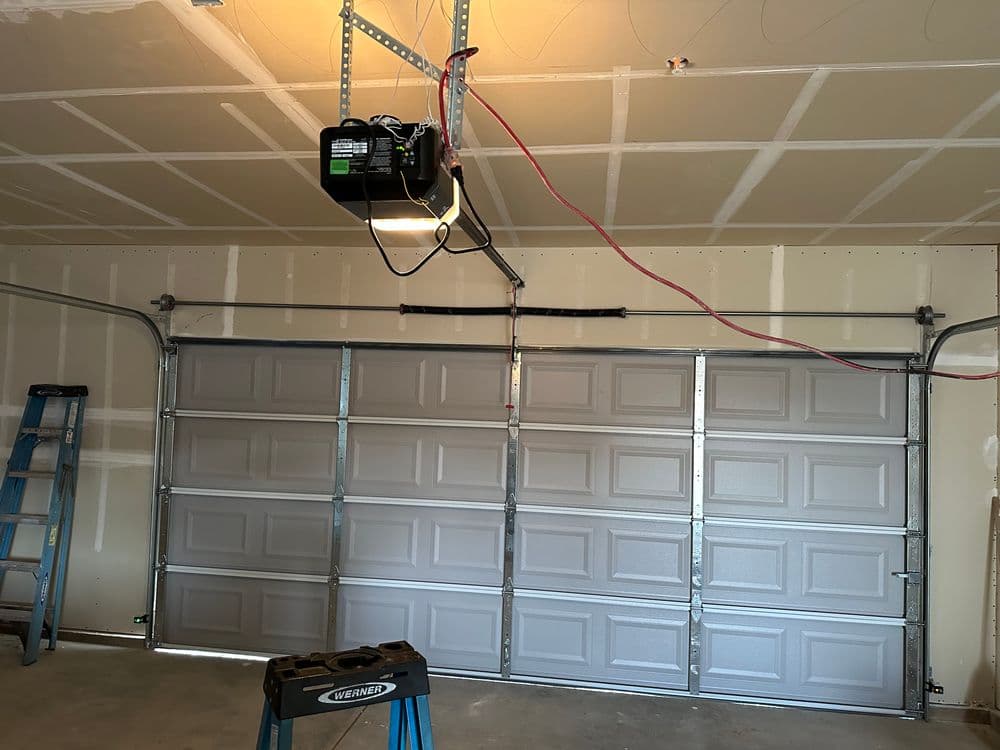 Newly installed garage door opener with modern design in a freshly finished garage interior.