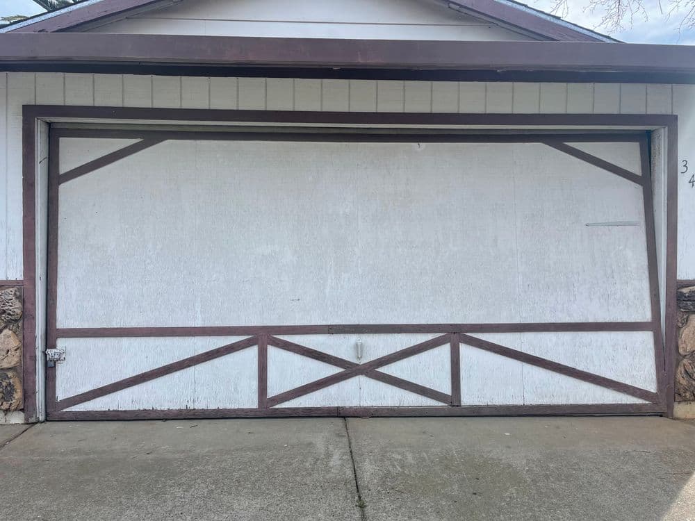 Old wooden garage door with a decorative brown trim on a residential home.