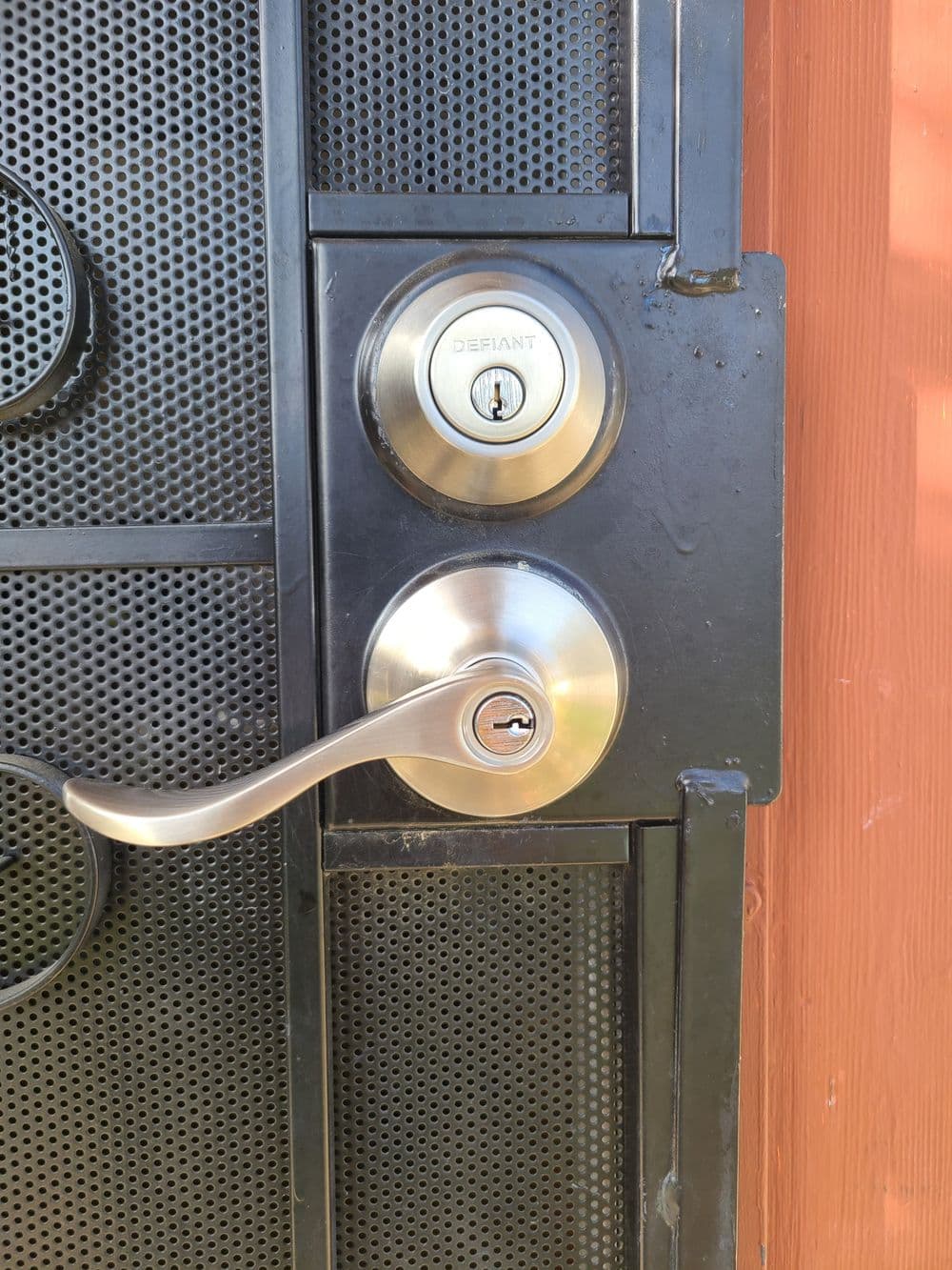 Close-up of a security door lockset with a lever handle and keyhole on a wooden door.