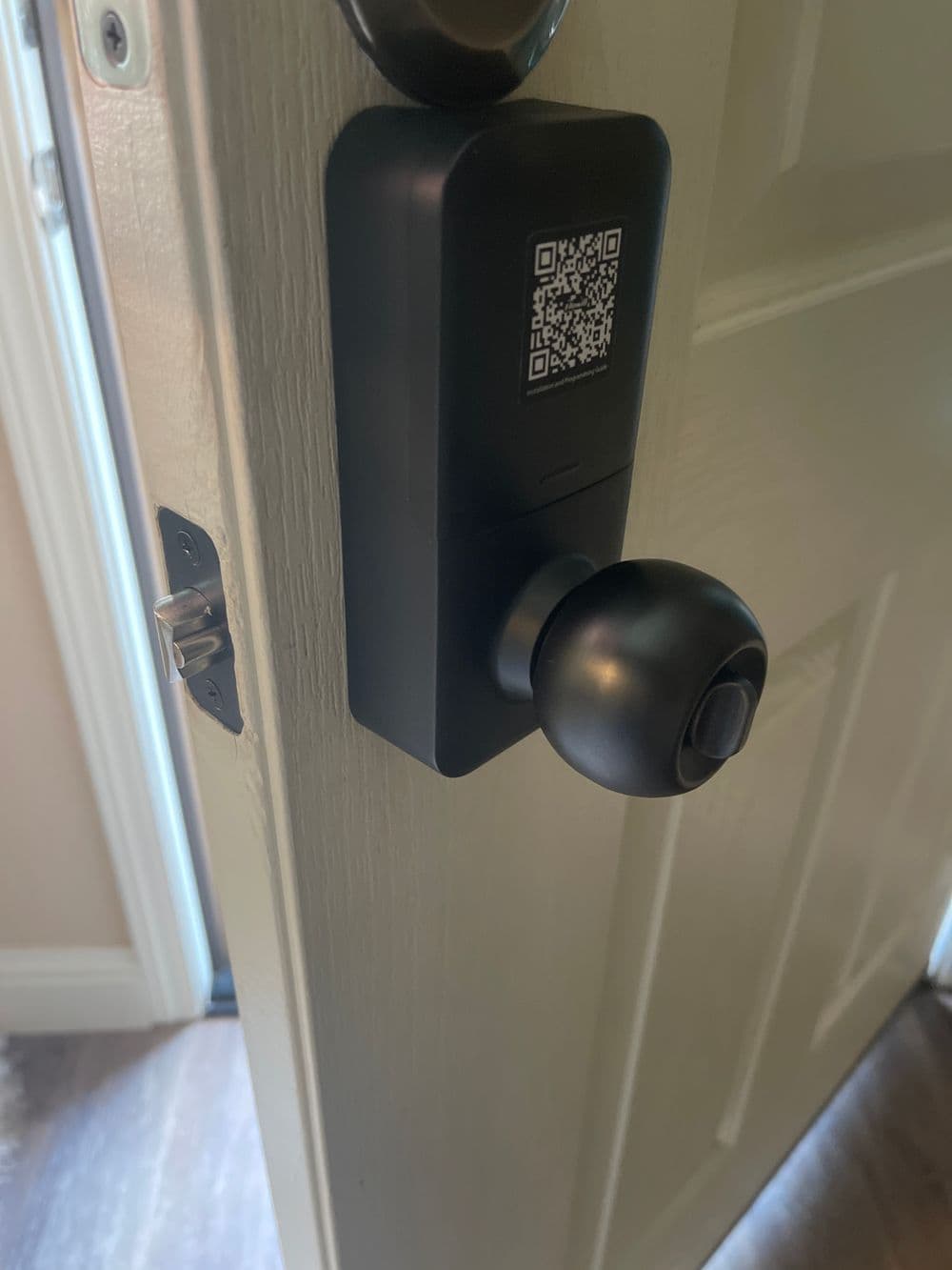 Smart door lock with QR code, showcasing modern security technology on a wooden door.