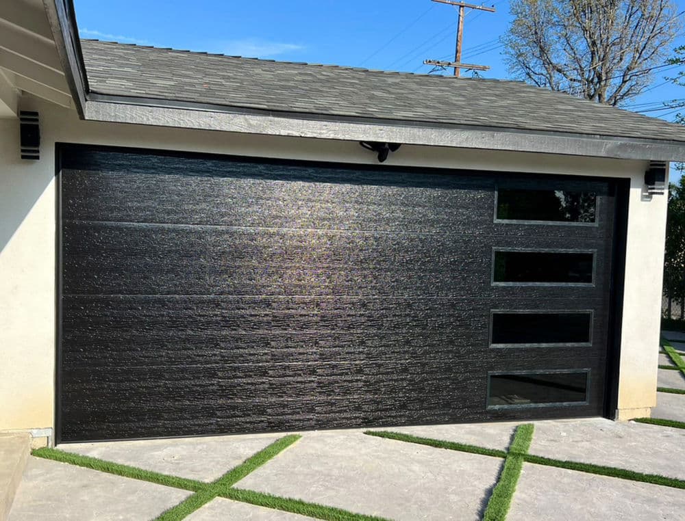 Modern black garage door with three glass windows, featuring sleek design and textured finish.