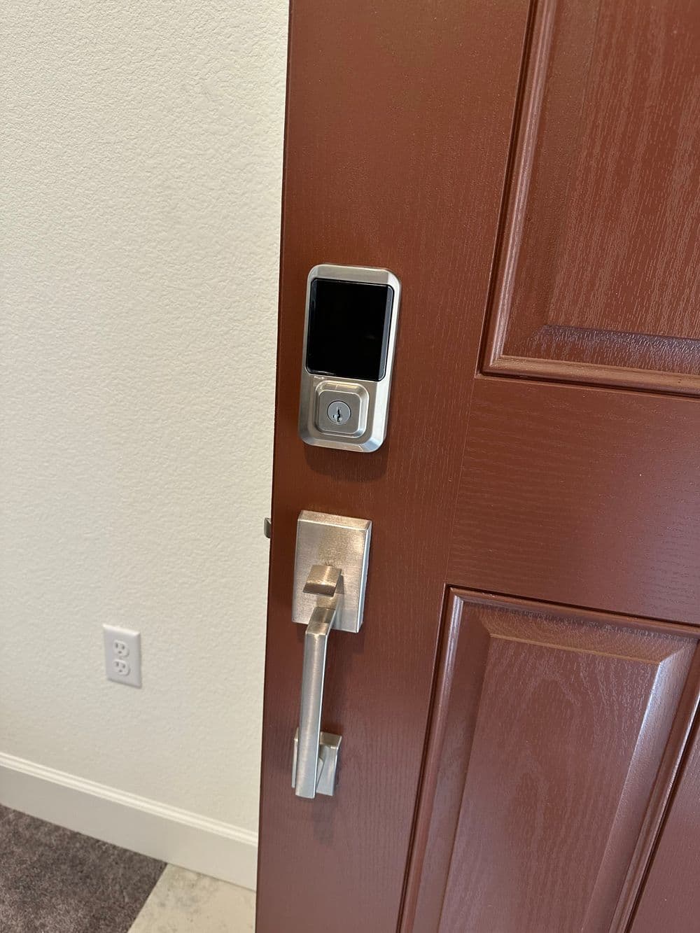 Smart lock on a wooden door with a sleek handle and modern design. Security technology at home.