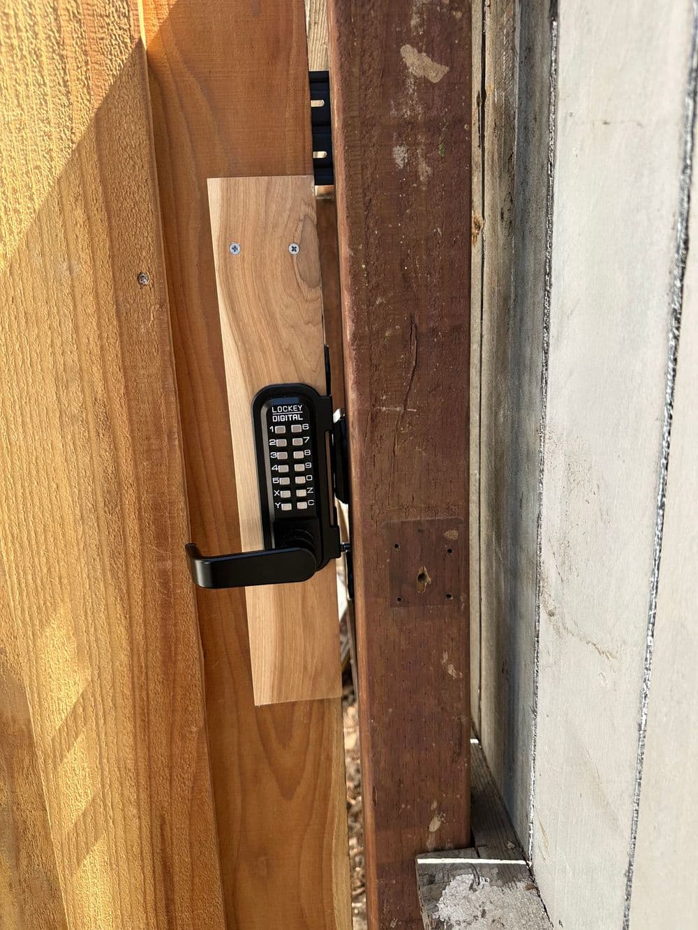 Keyless entry lock installed on a wooden gate shows security features and design details.