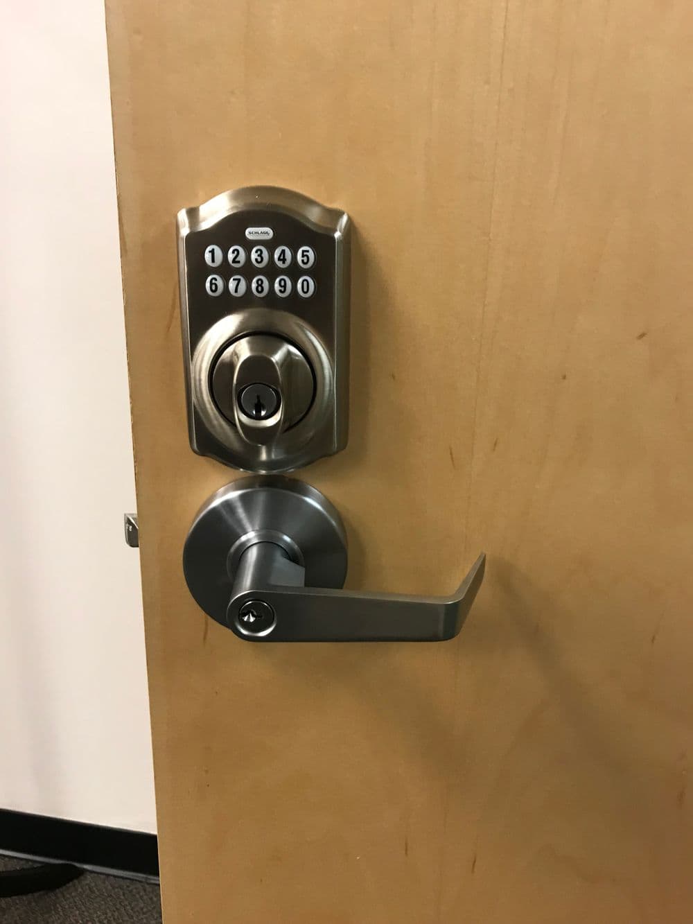 Keyless door lock with keypad and lever handle on wooden door. Modern security feature.