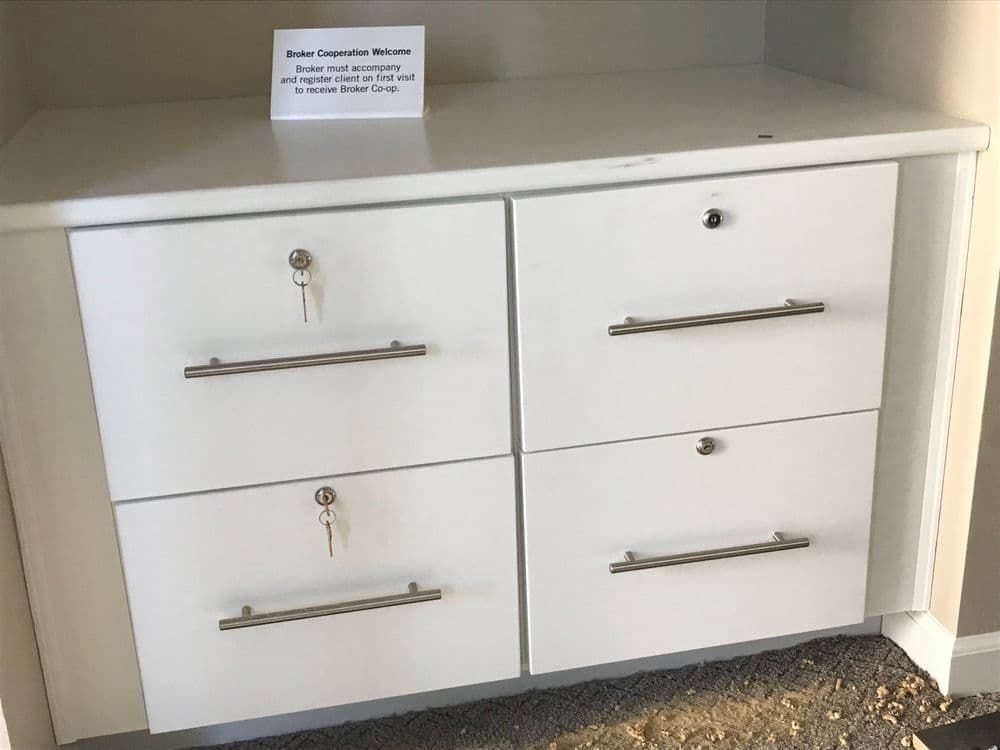 White dresser with four drawers and a welcome sign for Broker Cooperative.