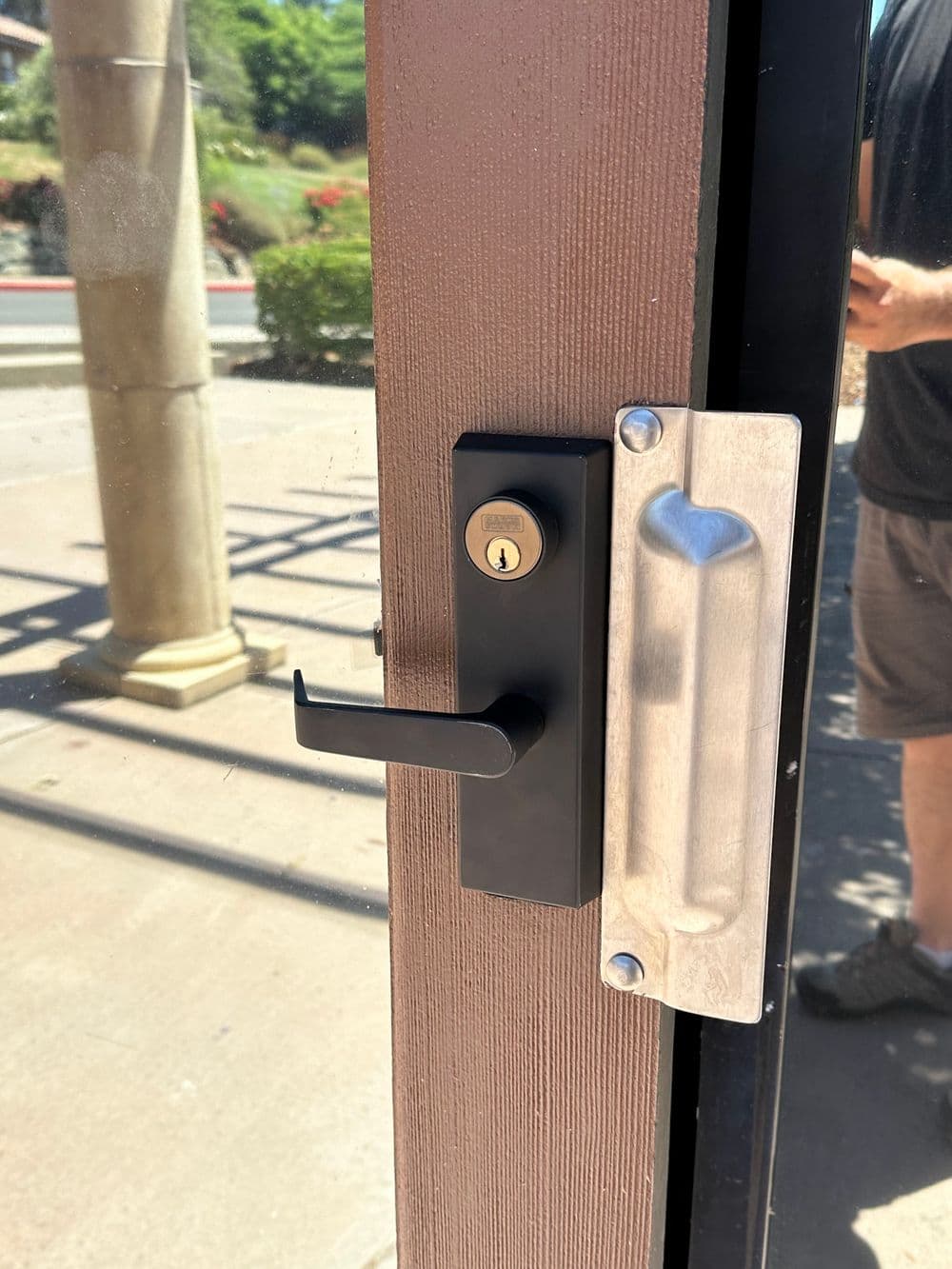 Black door lock and handle on a glass door, ensuring security and easy access.