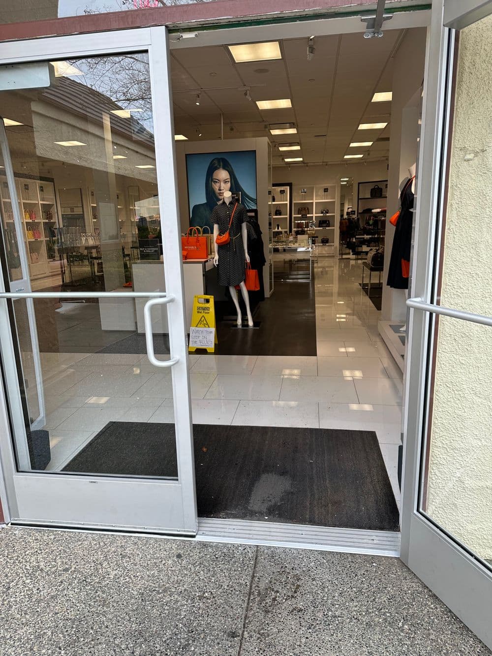 Entrance of a retail store featuring a mannequin display and colorful accessories inside.