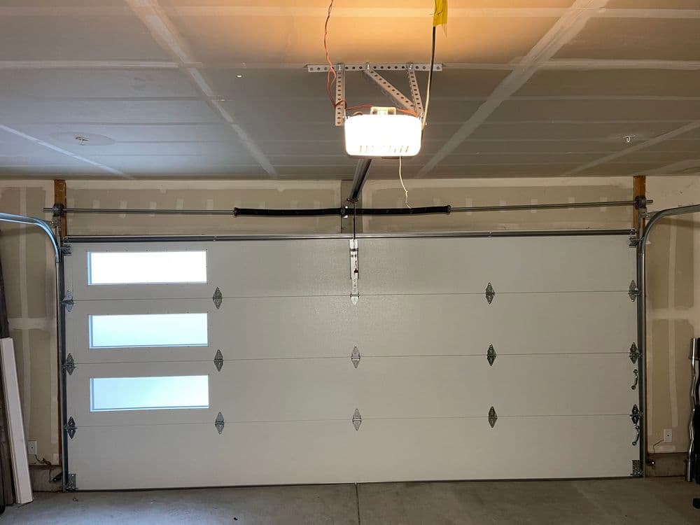 Interior view of a modern garage with a white sectional door featuring three windows.