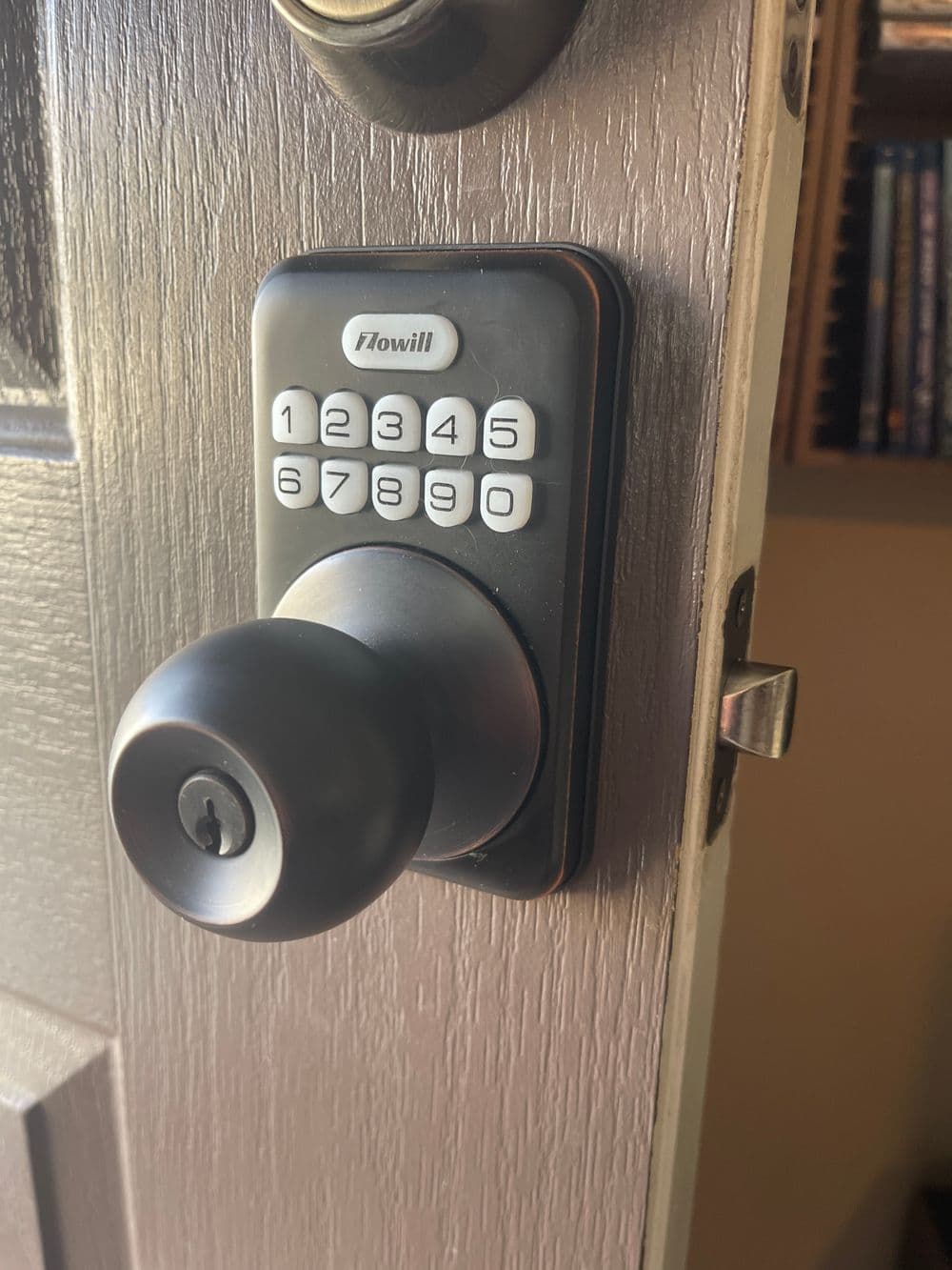 Digital keypad door lock mounted on a residential door with a traditional doorknob.