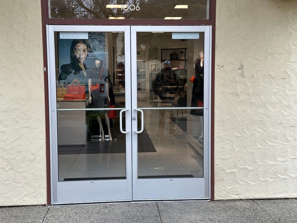 Storefront entrance displaying a stylish mannequin and fashionable bags.
