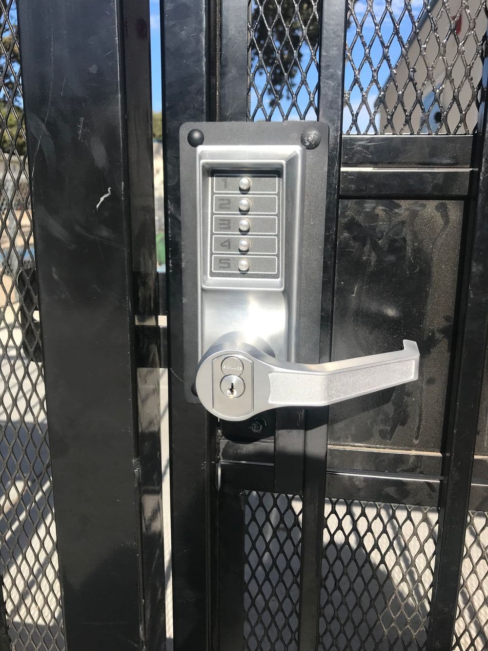 Keypad lock on a metal gate with a lever handle, providing secure access control.