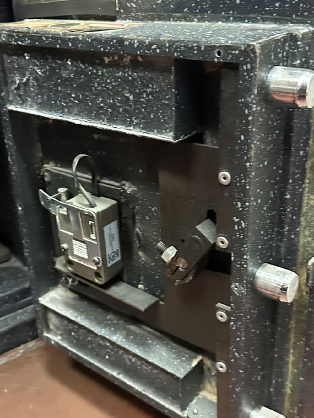Close-up of a black, vintage safe with a key lock and worn surface details.