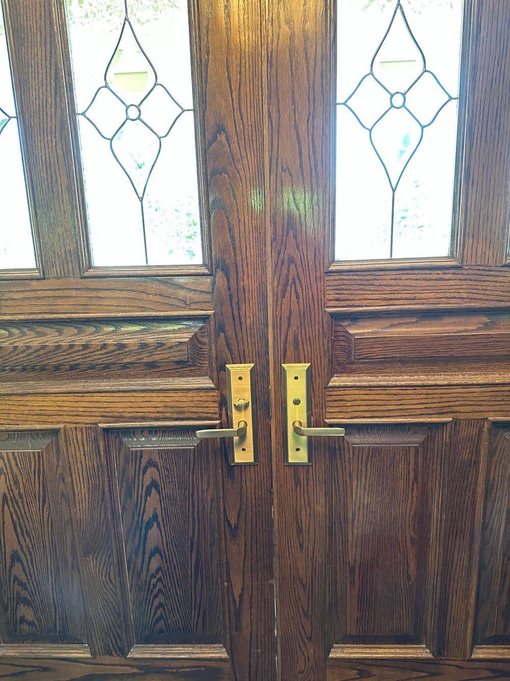 Elegant wooden double doors with brass handles and decorative glass panels.