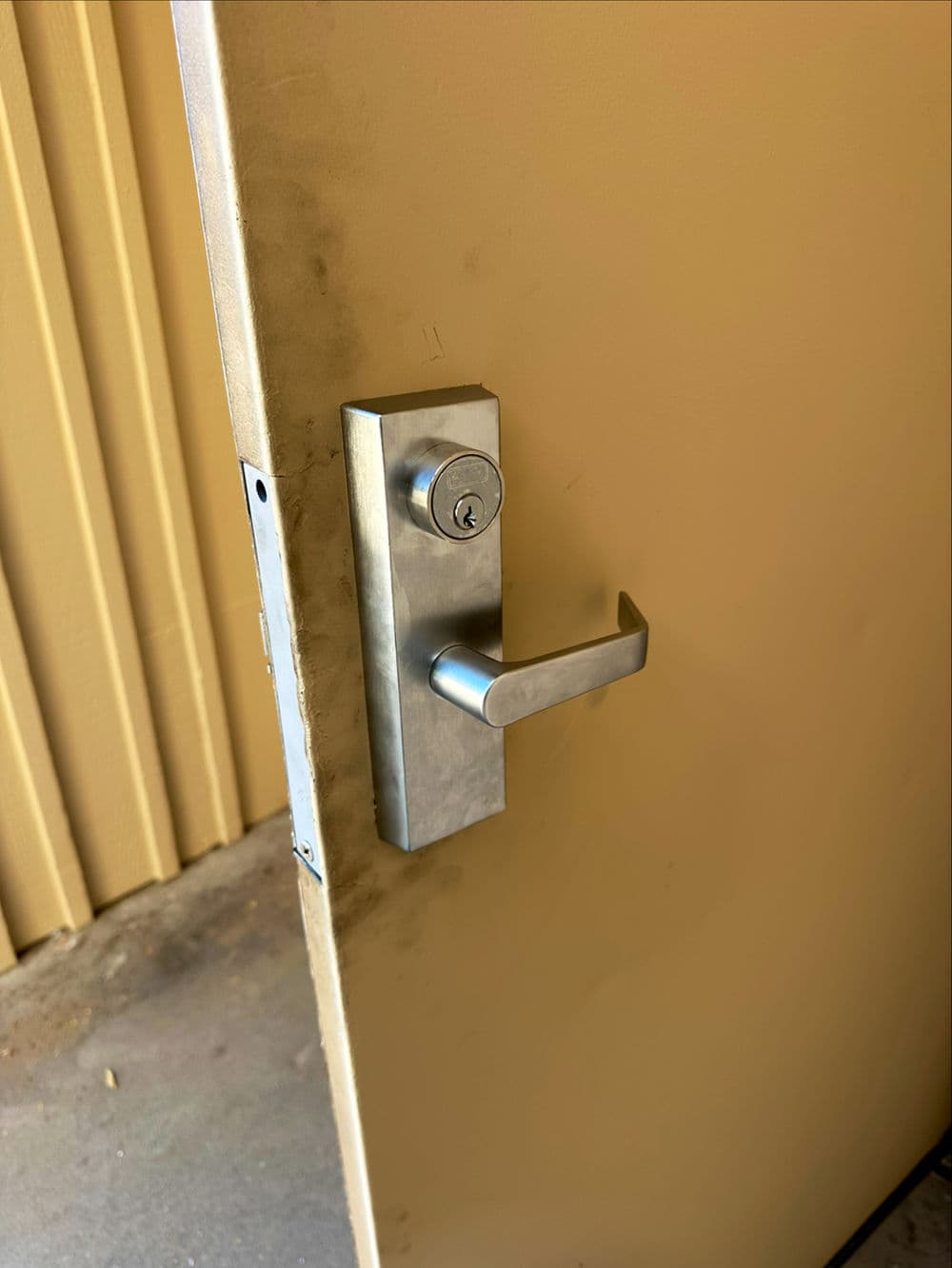 Close-up of a metallic door handle and lock on a yellow door, emphasizing security and accessibility.