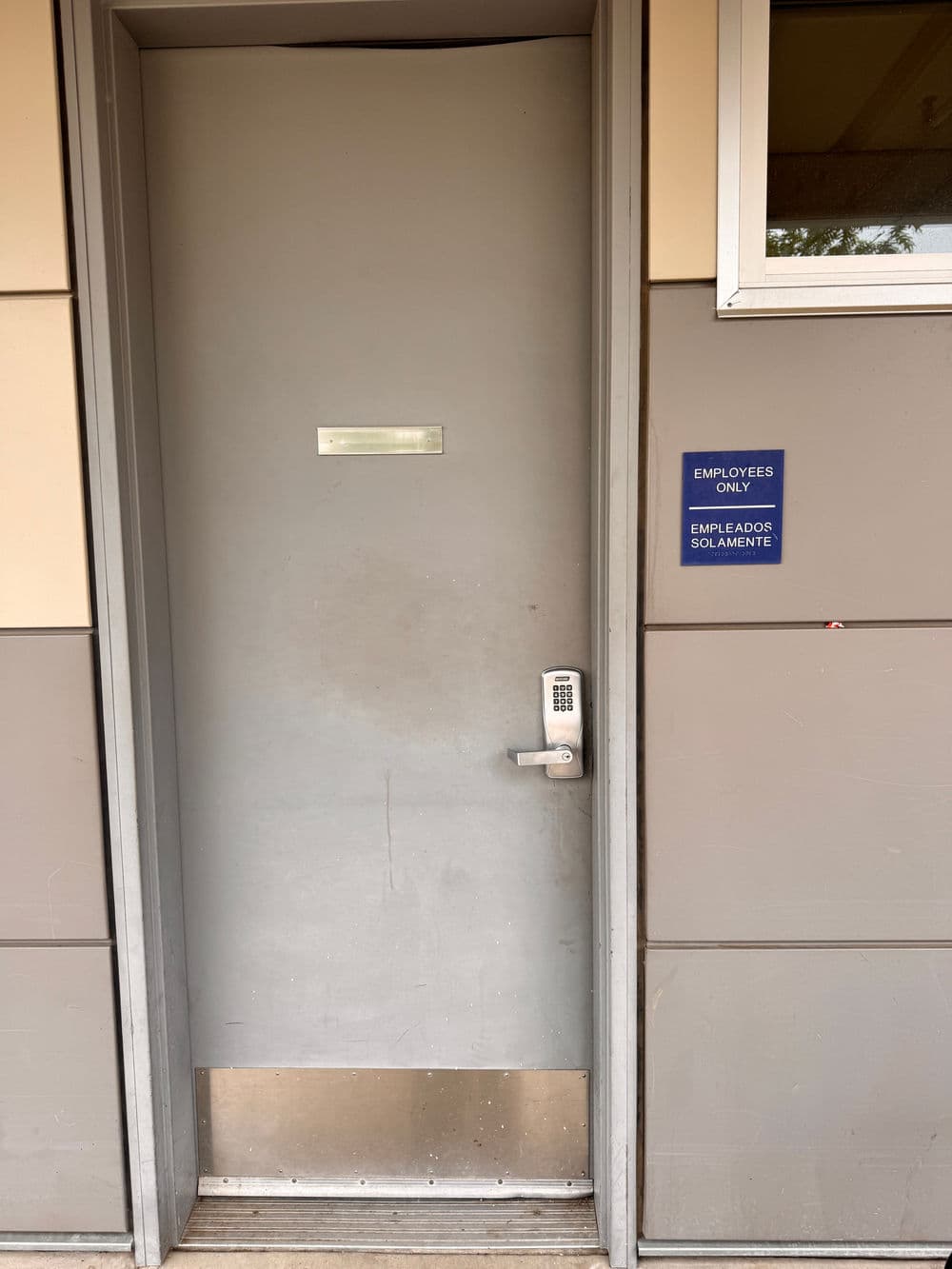 Gray door labeled 'Employees Only' with keypad entry, located at a commercial building.