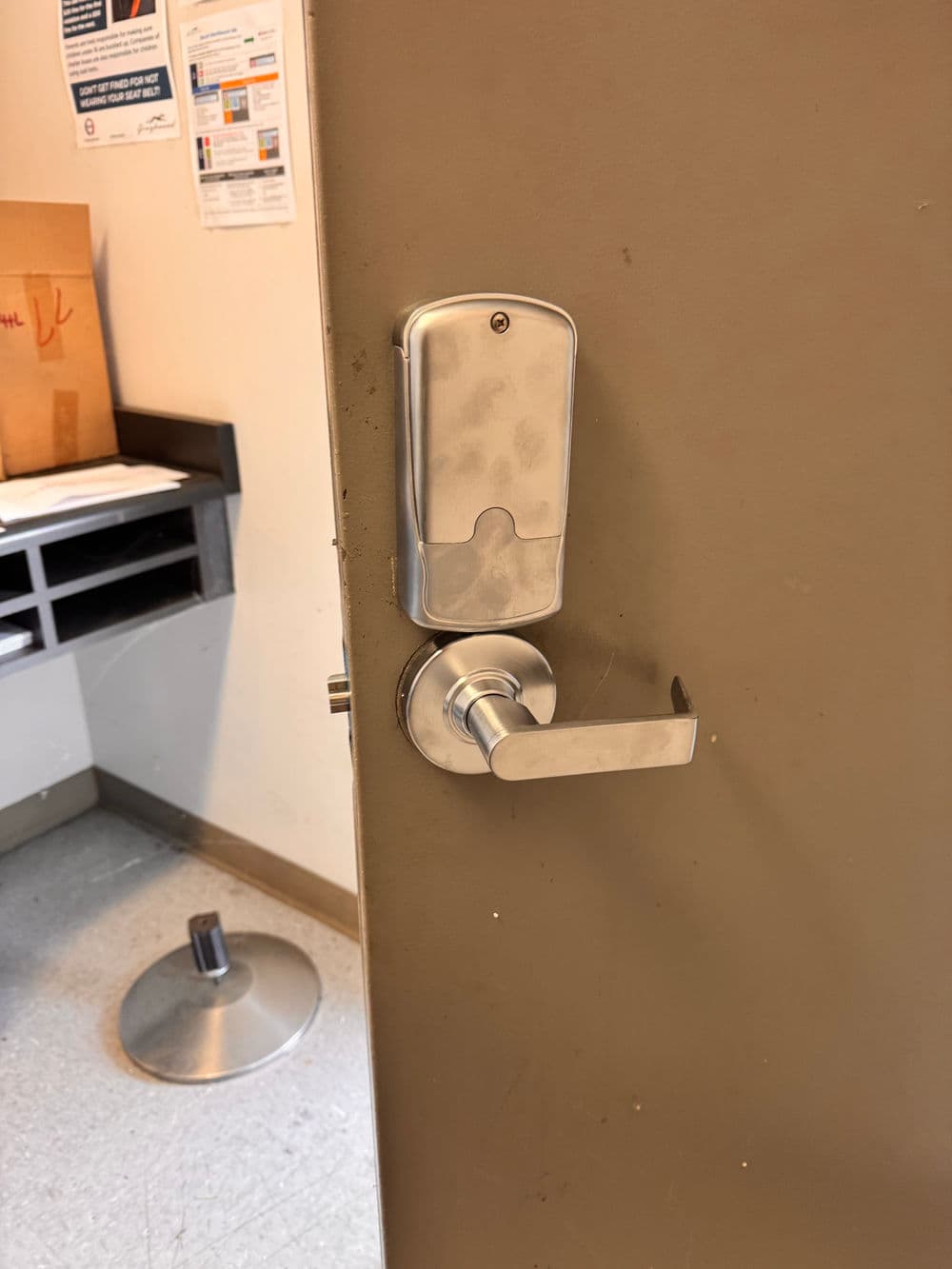 Modern door lock with handle on a brown door in an office setting.