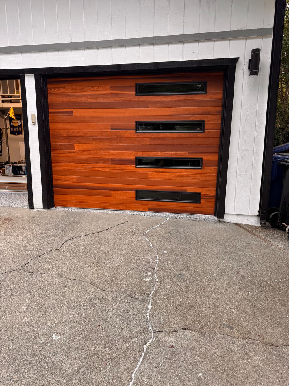 Modern wooden garage door with horizontal slats and decorative glass panels.