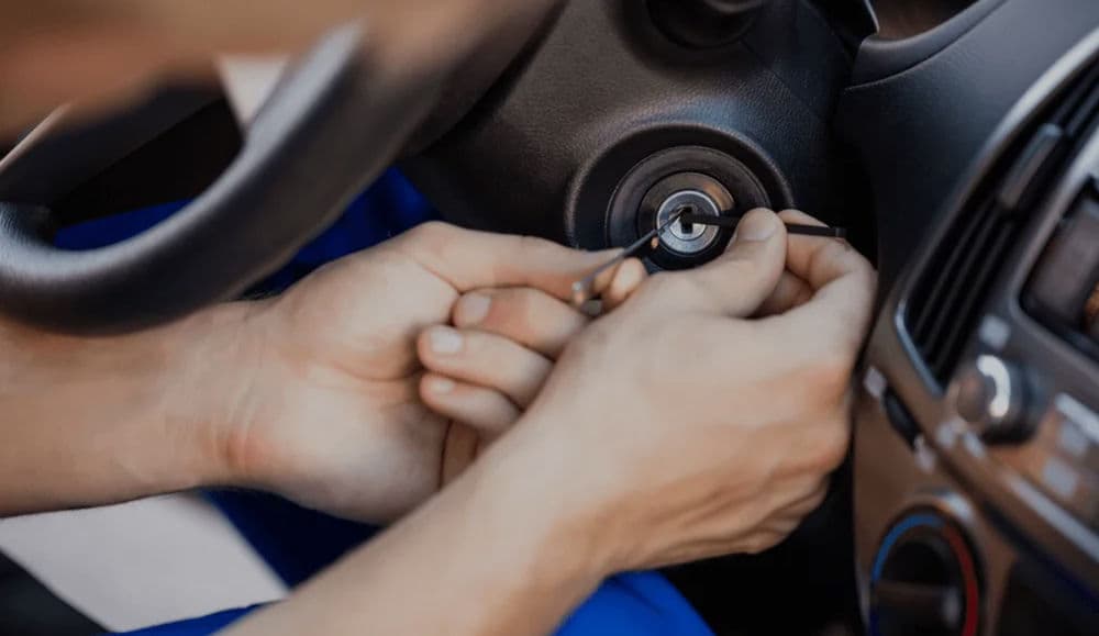 Close-up of hands replacing a car ignition key cylinder inside a vehicle.